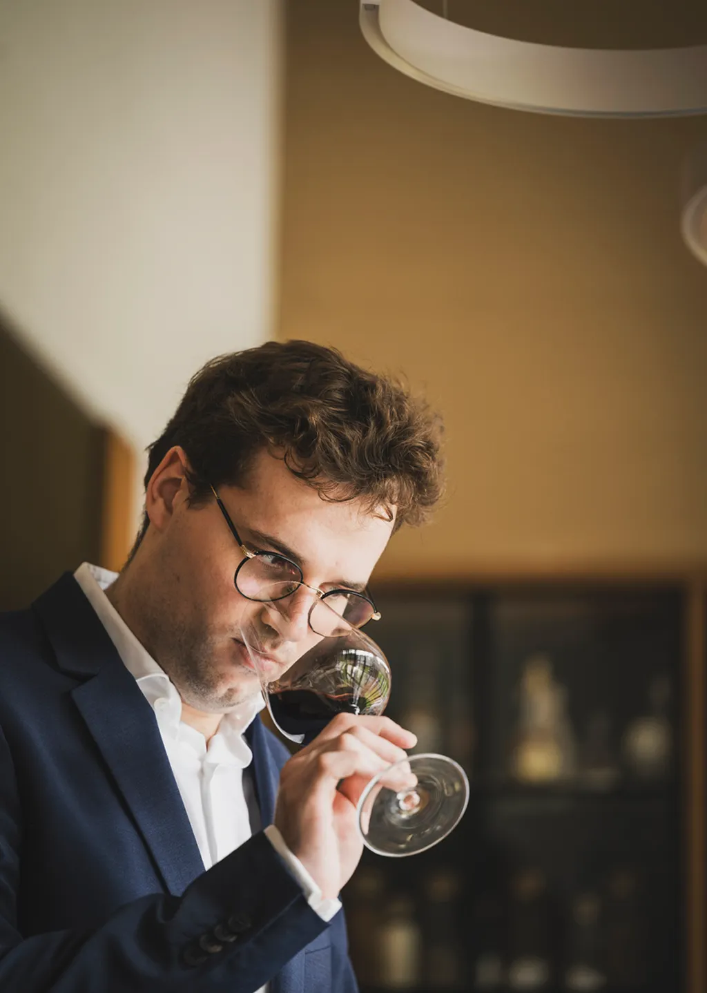Wijnexpertise van sommelier Yoerik Een sommelier met bril en blauw pak ruikt geconcentreerd aan een glas rode wijn.
